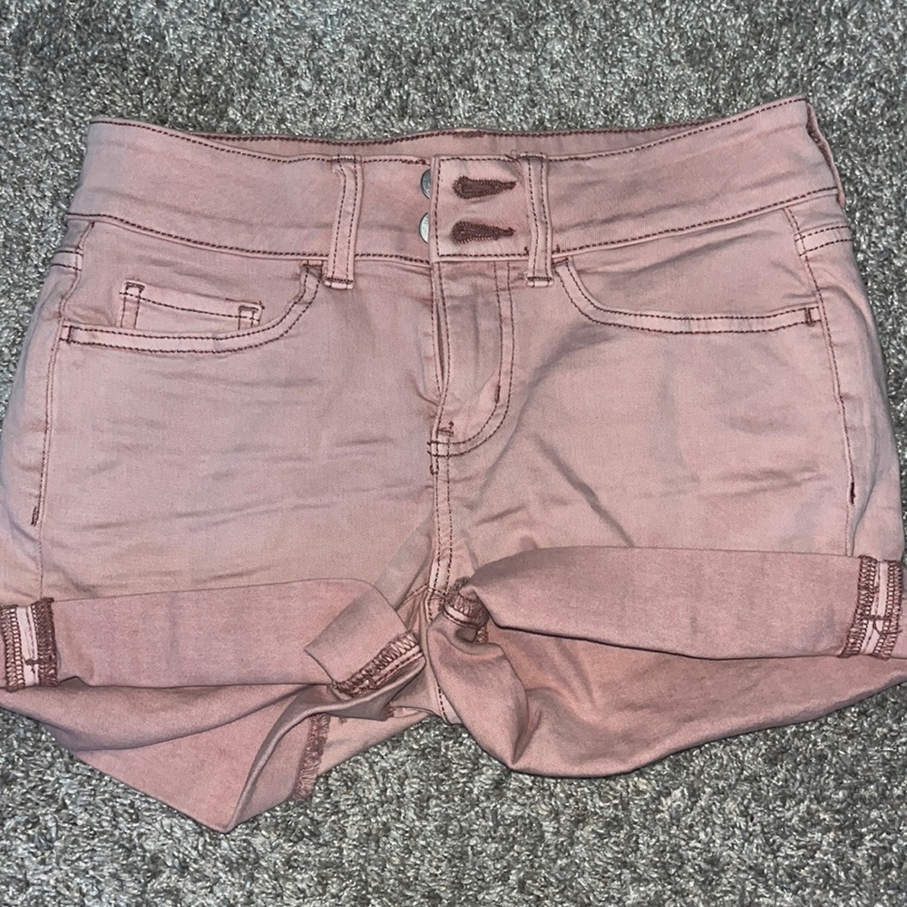 Pink denim shorts that have a zipper and two buttons